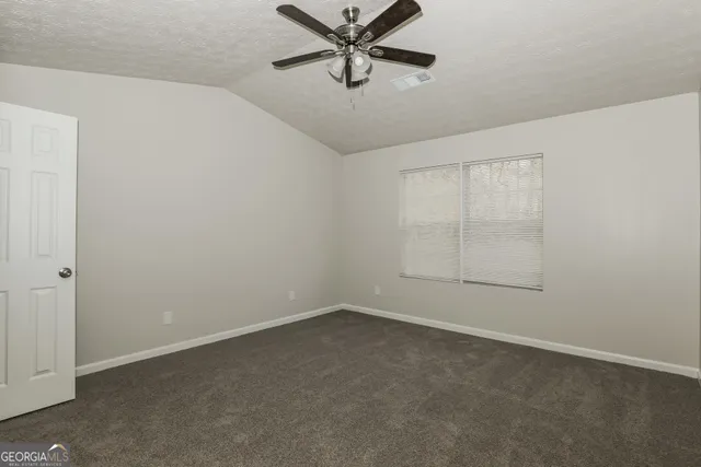 an empty room with a ceiling fan and windows