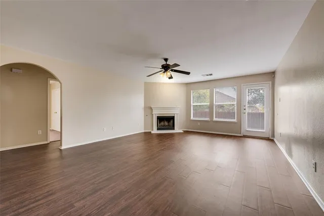 an empty room with wooden floor fireplace and windows