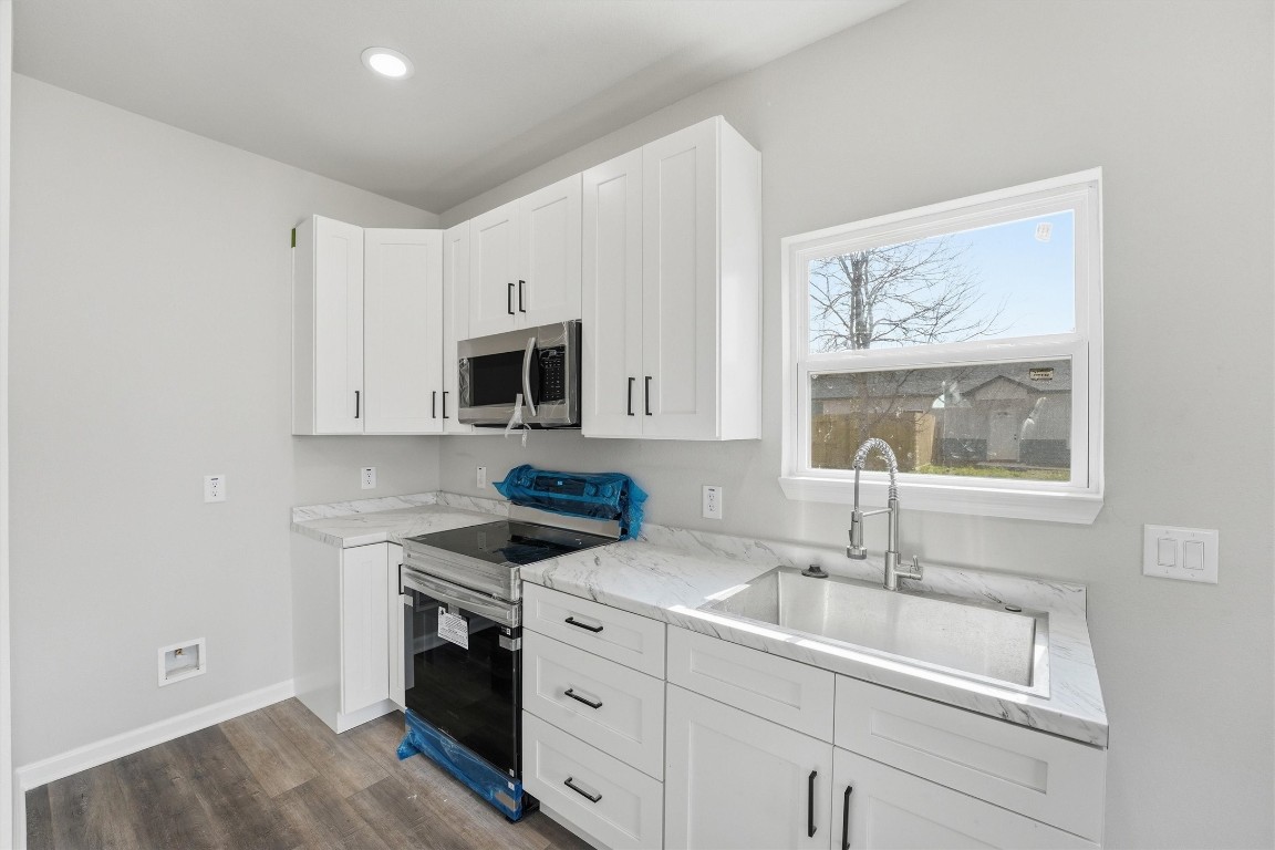 2250 Cable Avenue Beaumont, TX 77703 - Photo 9 of 21 a kitchen with white cabinets a sink and a stove with wooden floor