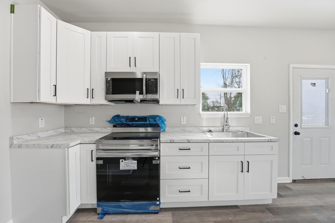 2250 Cable Avenue Beaumont, TX 77703 - Photo 10 of 21 a kitchen with white cabinets and a stove with wooden floor