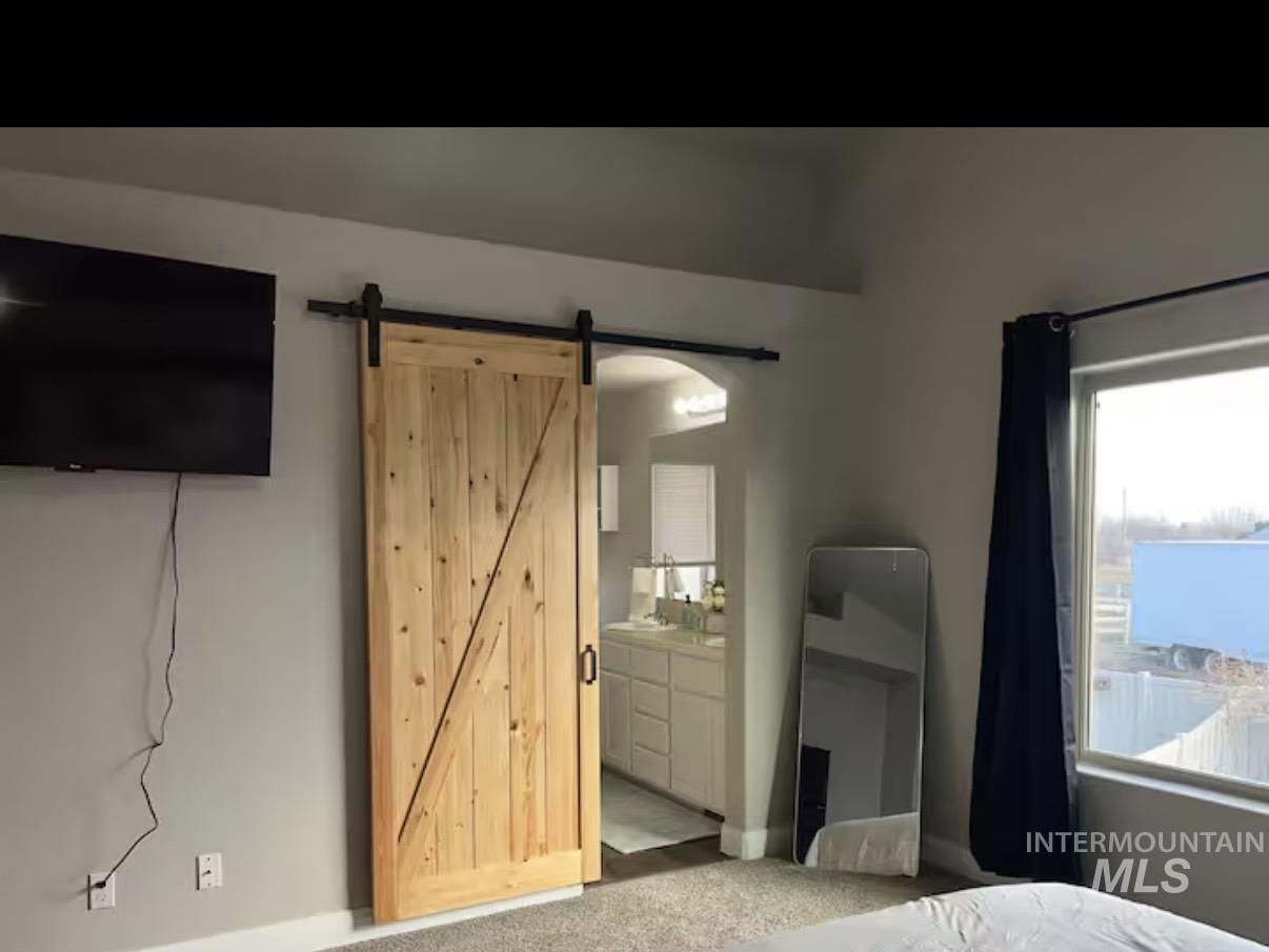 723 Stallion Springs Way Middleton, ID 83644 - Photo 18 of 50 Bedroom with ensuite bathroom, carpet floors, and a barn door