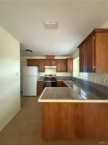 a kitchen with stainless steel appliances granite countertop a refrigerator a sink and a stove