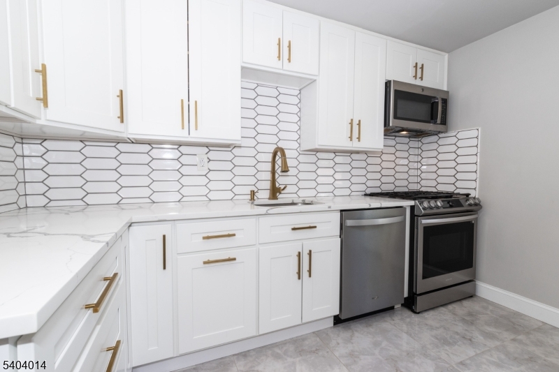 445 Morris Avenue Springfield, NJ 07081 - Photo 2 of 15 a kitchen with granite countertop white cabinets sink and stainless steel appliances