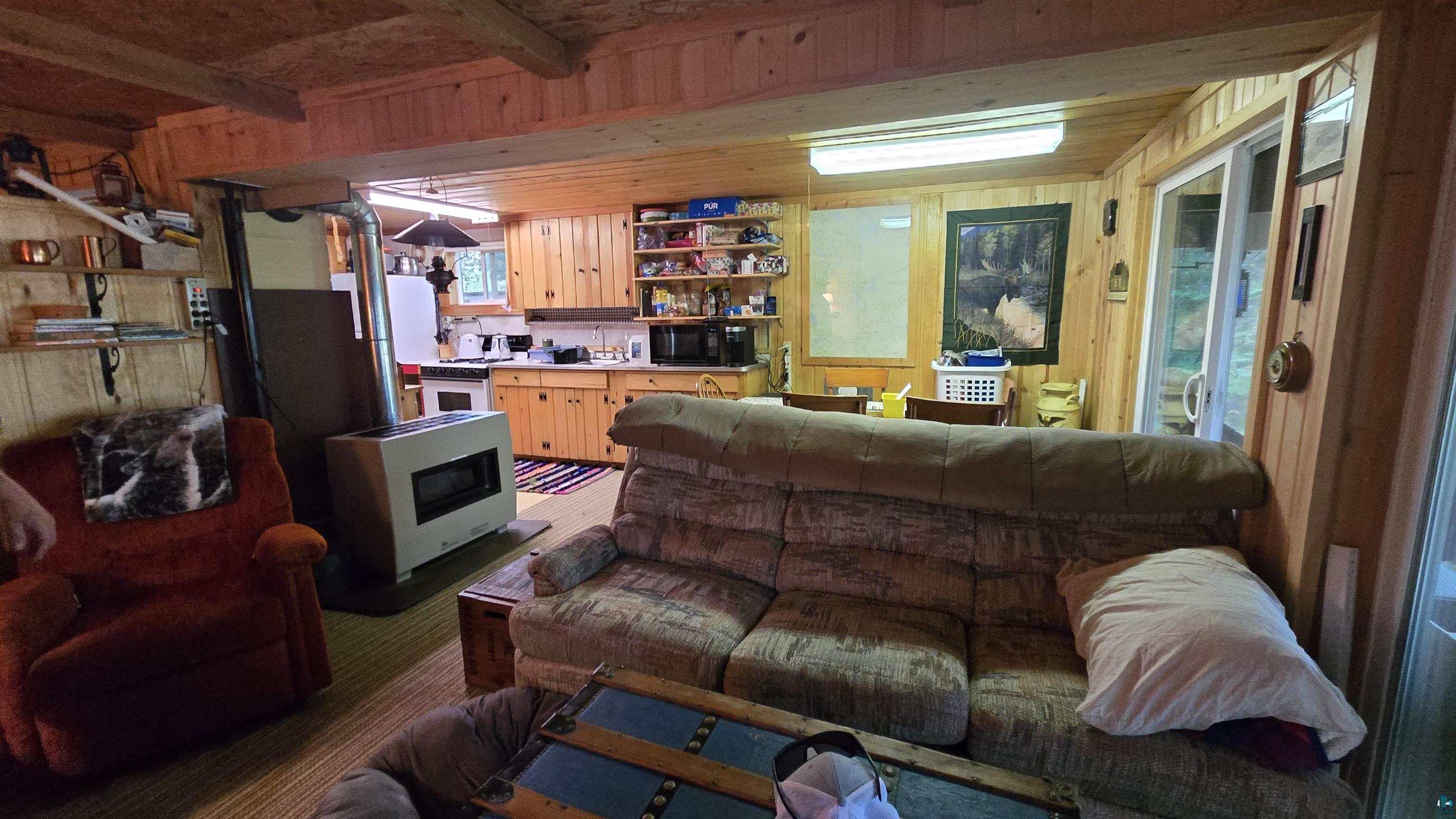 7178 Gold Mine Road Orr, MN 55771 - Photo 16 of 36 Living room featuring wooden walls, a wood stove, and beamed ceiling