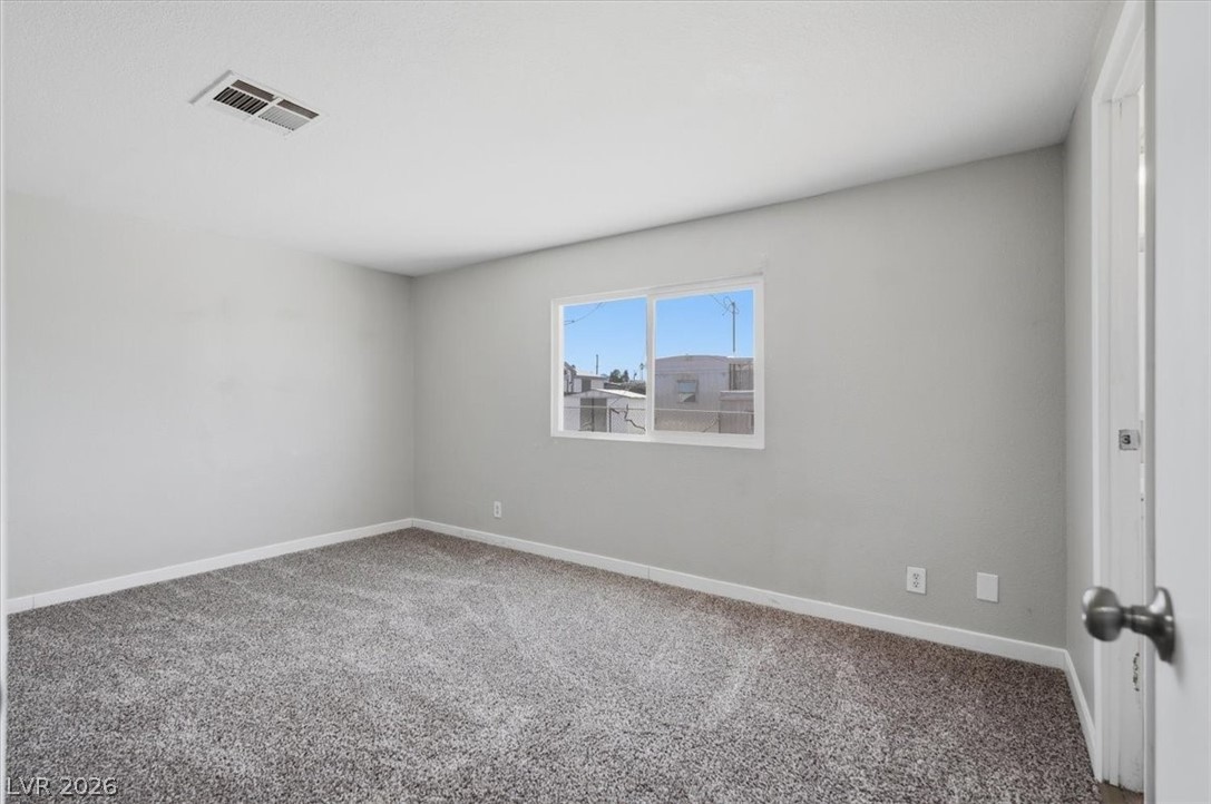 283 Aztec Lane Henderson, NV 89015 - Photo 15 of 21 A quiet bedroom offering new gray carpet, pristine walls, and a large window for ample light.