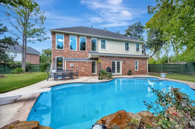 a view of a house with pool fire pit a patio and a yard