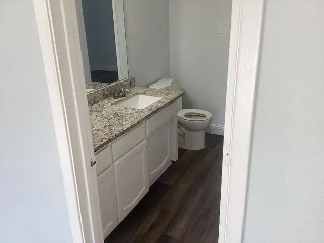 a bathroom with a granite countertop toilet and a sink