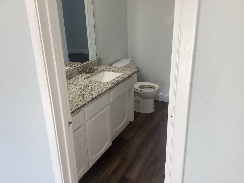7512 Chapin Road Fort Worth, TX 76116 - Photo 19 of 25 a bathroom with a granite countertop sink a toilet and a mirror