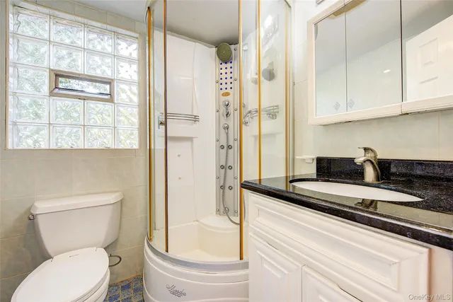 a bathroom with a granite countertop sink a toilet a mirror and a shower