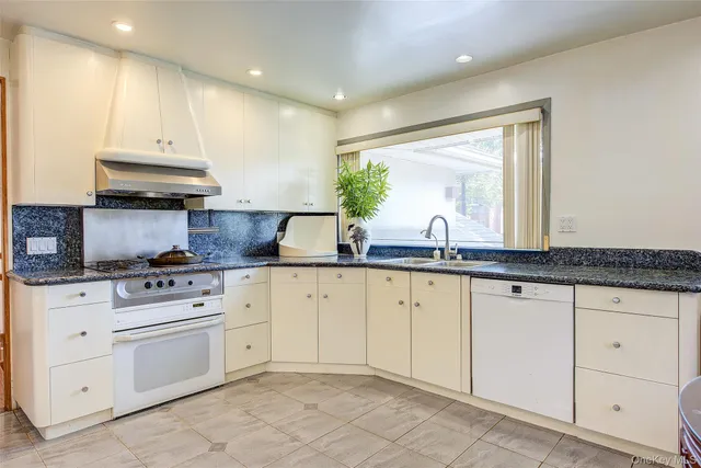 a kitchen with granite countertop white cabinets white appliances and a sink