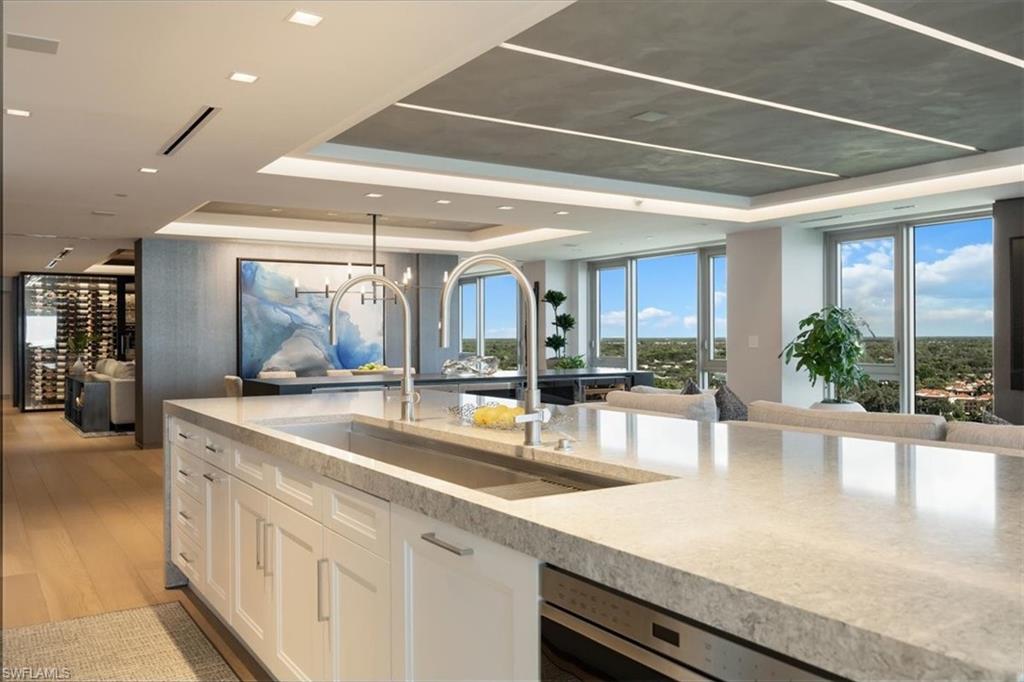 6897 Grenadier Boulevard, Unit 1701 Naples, FL 34108 - Photo 10 of 50 a large kitchen with stainless steel appliances a large counter top and a view of living room