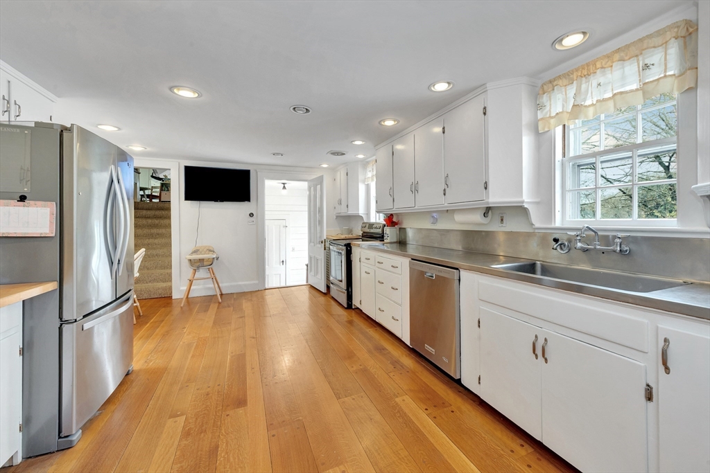 505 Essex Street Hamilton, MA 01982 - Photo 15 of 37 a kitchen with stainless steel appliances granite countertop a sink a stove a refrigerator and island with wooden floor