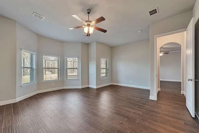 a view of an empty room with wooden floor and window