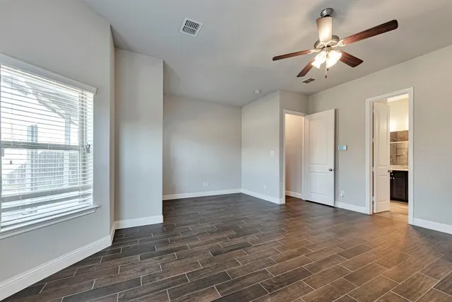 an empty room with wooden floor chandelier and windows