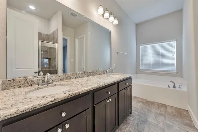 a bathroom with a granite countertop double vanity sink and a mirror