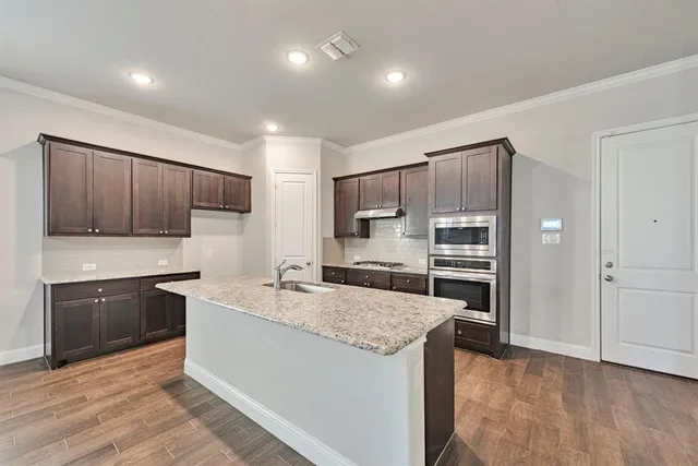 a kitchen with granite countertop a sink stove and refrigerator