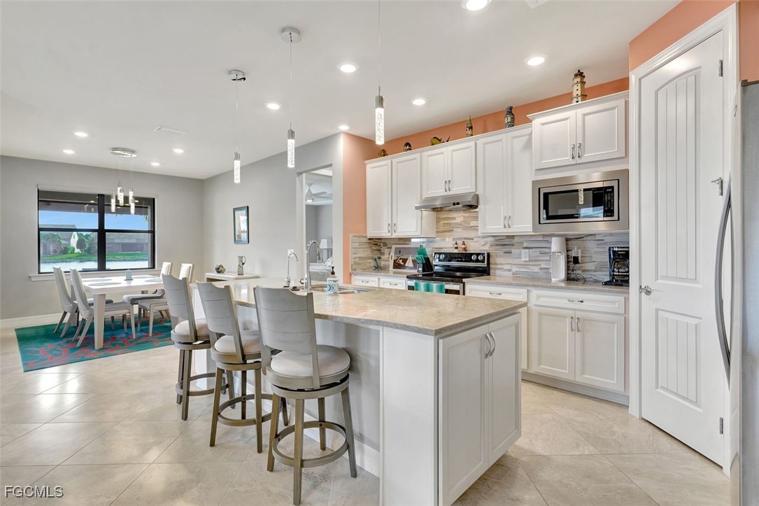 11812 Clifton Terrace Fort Myers, FL 33913 - Photo 8 of 46 a kitchen with kitchen island granite countertop a stove a sink a dining table and chairs