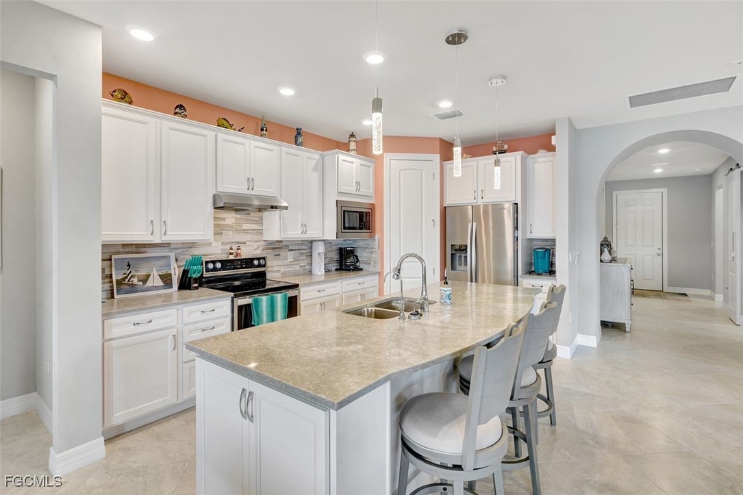 11812 Clifton Terrace Fort Myers, FL 33913 - Photo 9 of 46 a kitchen with stainless steel appliances kitchen island granite countertop a sink refrigerator and cabinets