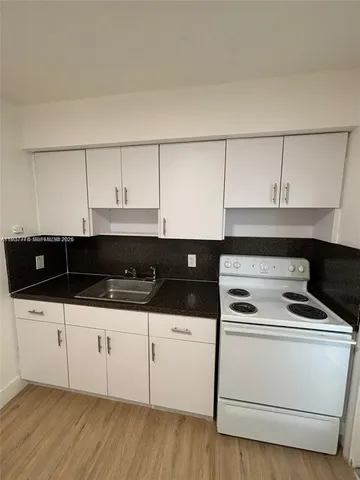 a kitchen with white cabinets and appliances