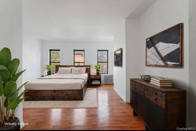 a bedroom with a bed table chair and a potted plant