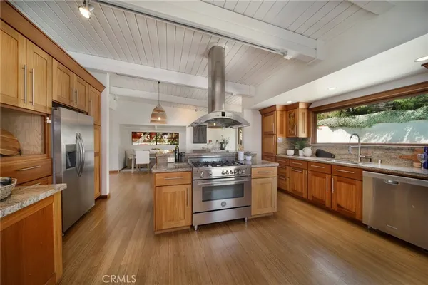 a kitchen with stainless steel appliances granite countertop hardwood floor sink stove dining table chairs and granite counter top