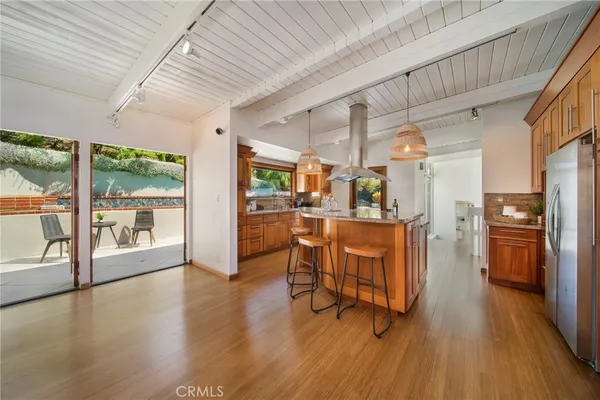 a living room with stainless steel appliances kitchen island hardwood floor and a large window
