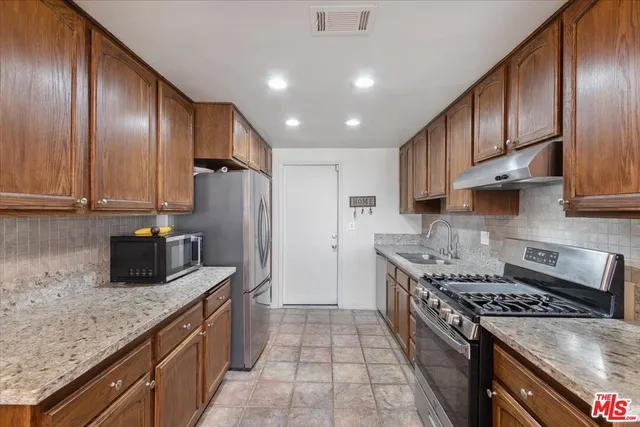a kitchen with stainless steel appliances granite countertop a sink stove and refrigerator
