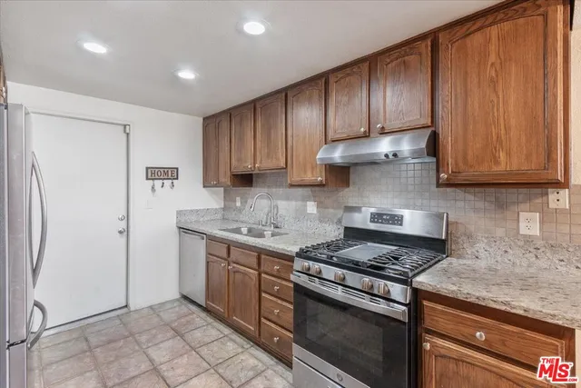a kitchen with stainless steel appliances granite countertop a stove a refrigerator and a cabinets