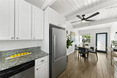 a kitchen with granite countertop a refrigerator a stove a dining table and chairs with wooden floor