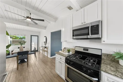 a kitchen with stainless steel appliances kitchen island granite countertop a stove and a wooden floors