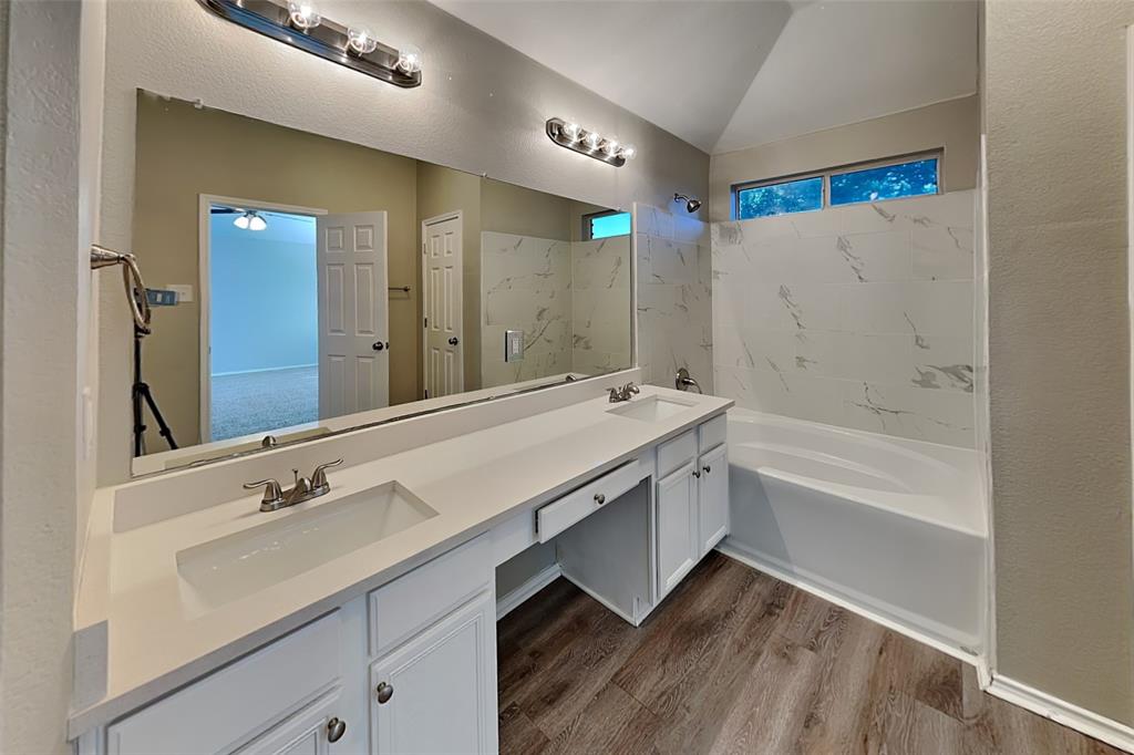 7016 Raintree Way Denton, TX 76210 - Photo 9 of 18 a spacious bathroom with a granite countertop sink a mirror and a bathtub