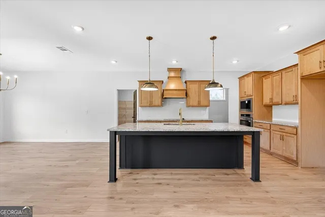 a kitchen with stainless steel appliances granite countertop a sink a stove and a wooden floor