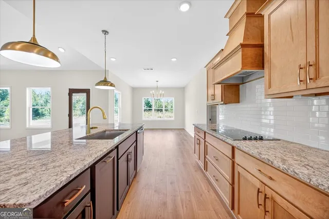 a kitchen with granite countertop kitchen island stainless steel appliances a sink stove and cabinets