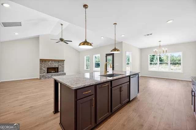 a kitchen with stainless steel appliances granite countertop a stove a sink and a wooden floor