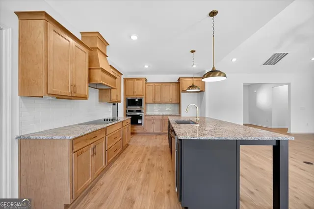 a kitchen with stainless steel appliances granite countertop a sink a stove and a wooden floors
