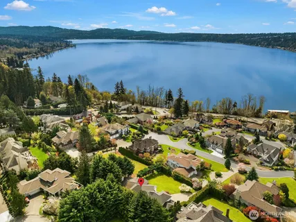 an aerial view of a house with a yard lake and trees all around