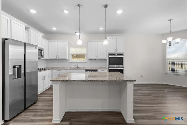 a kitchen with kitchen island a counter space stainless steel appliances and cabinets