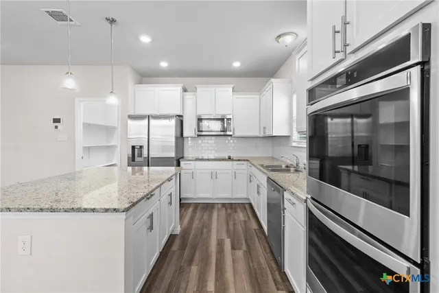 a kitchen with stainless steel appliances granite countertop a sink and a stove