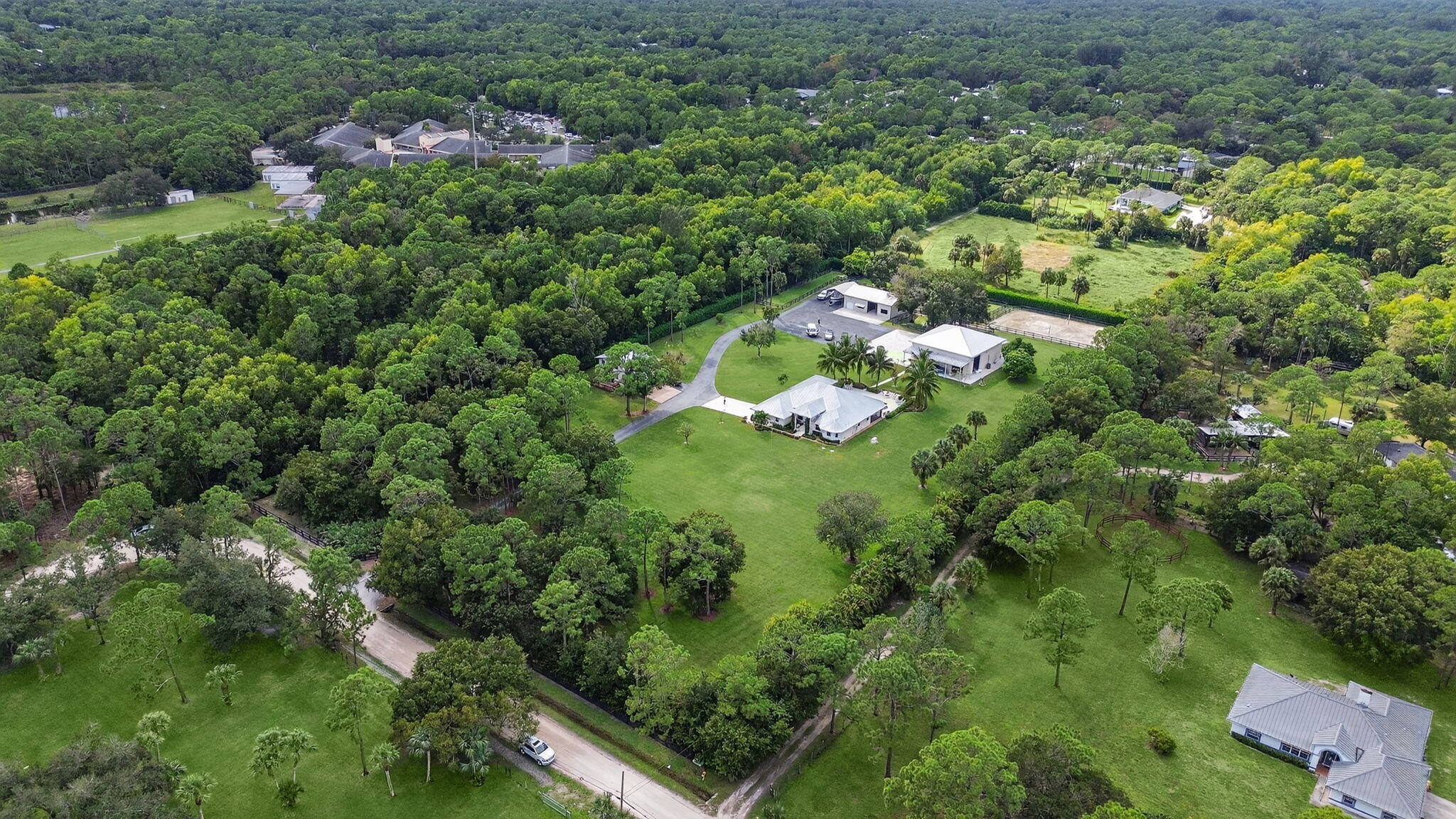 an aerial view of residential house with outdoor space and trees all around