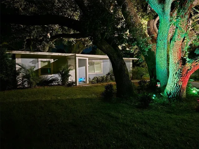 a view of a patio with table and chairs potted plants and large tree