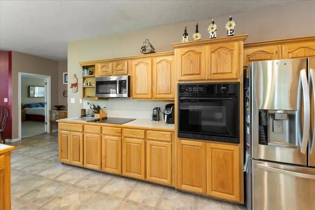 a kitchen with stainless steel appliances granite countertop a refrigerator a stove top oven and a sink