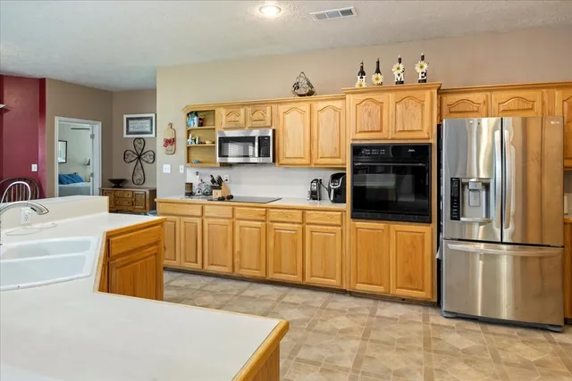 a kitchen with stainless steel appliances granite countertop a refrigerator a stove and a sink
