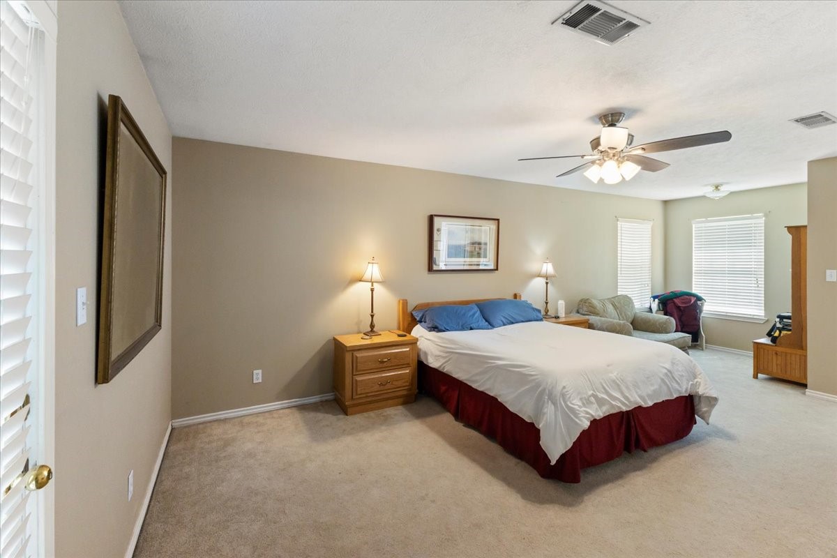 544 Meadow Lane Winnie, TX 77665 - Photo 25 of 38 a spacious bedroom with a bed and a chandelier