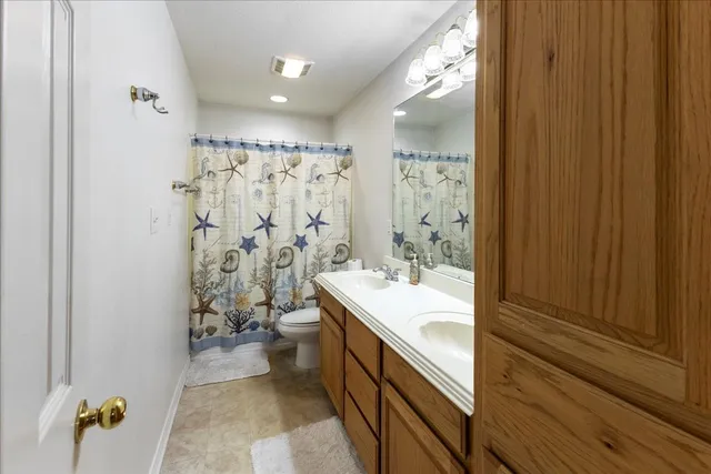 a bathroom with a double vanity sink toilet mirror and bathtub