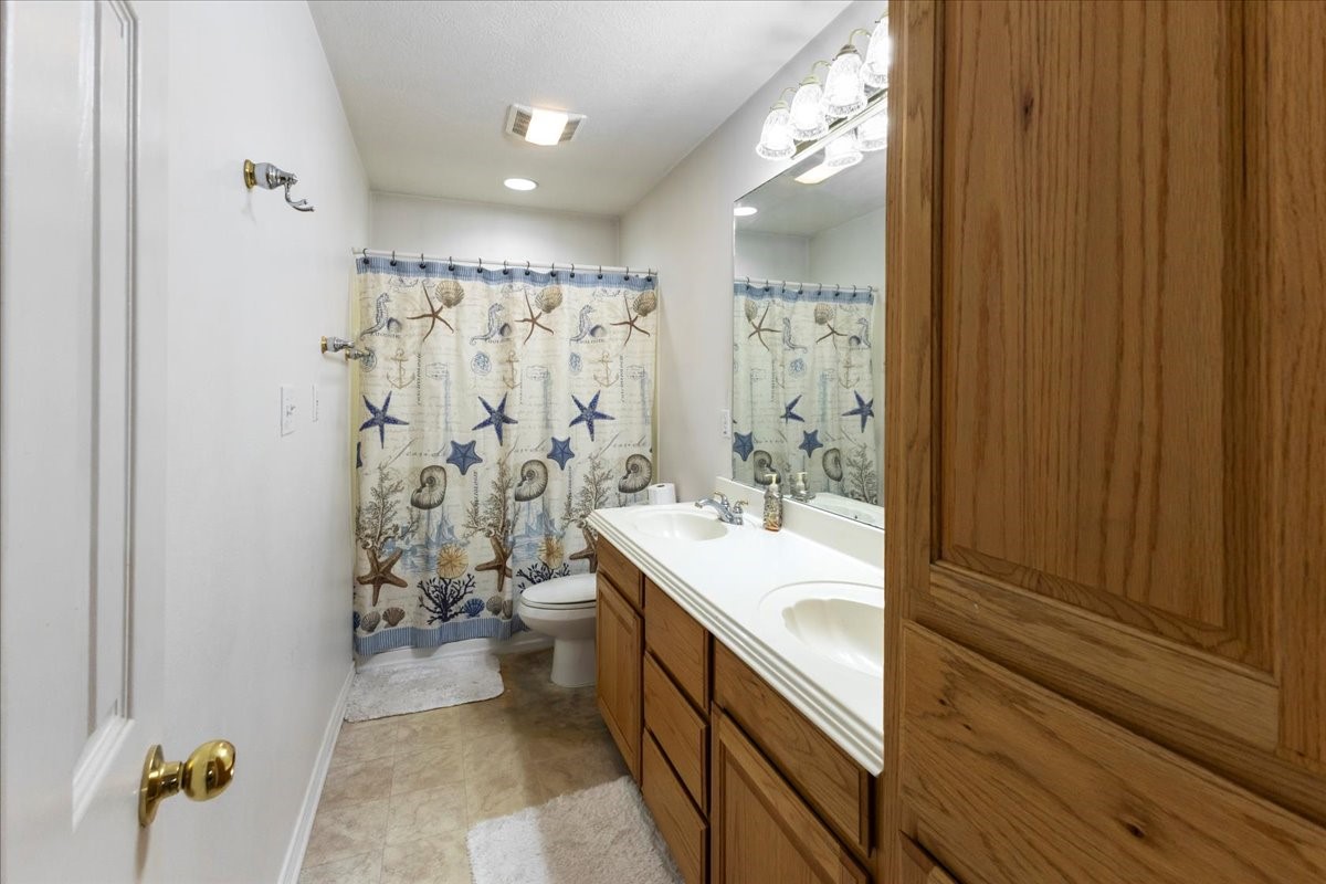 544 Meadow Lane Winnie, TX 77665 - Photo 32 of 38 a bathroom with a double vanity sink toilet mirror and bathtub