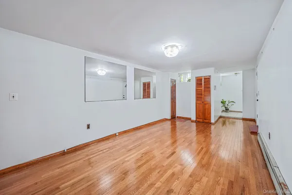a view of empty room with wooden floor and fan