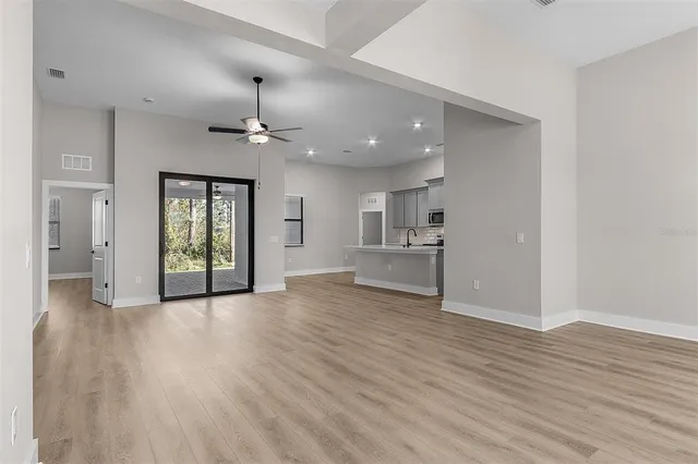 a view of an empty room with window and wooden floor