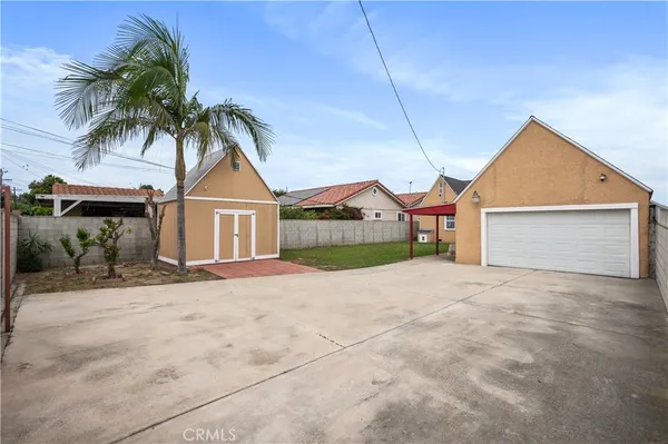 a view of yellow house with a yard and palm trees