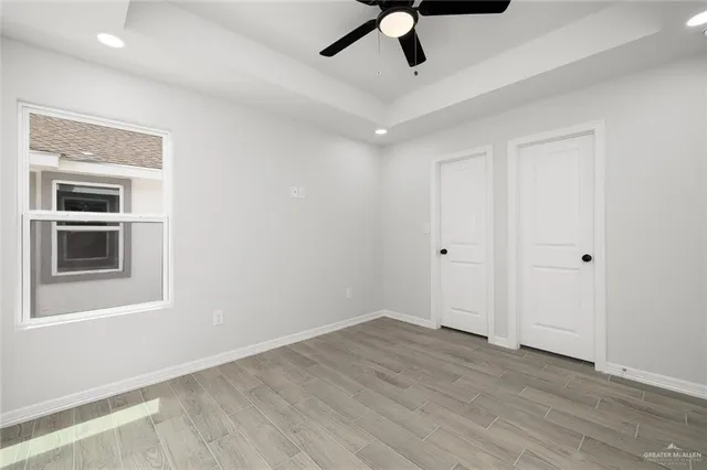 a view of empty room with wooden floor and ceiling fan