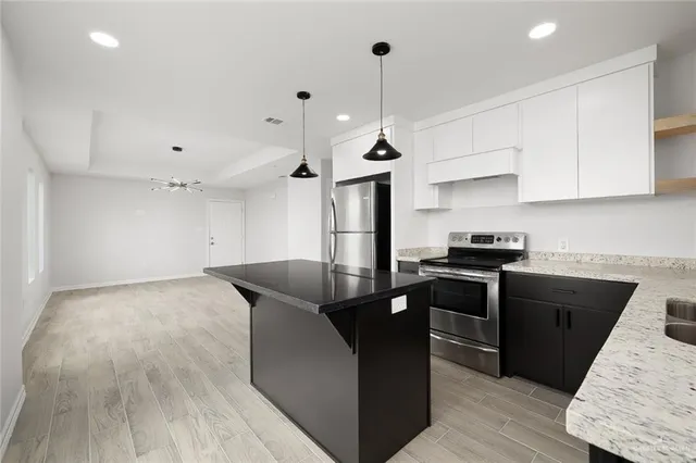 a kitchen with granite countertop a stove a sink a refrigerator and a wooden cabinets